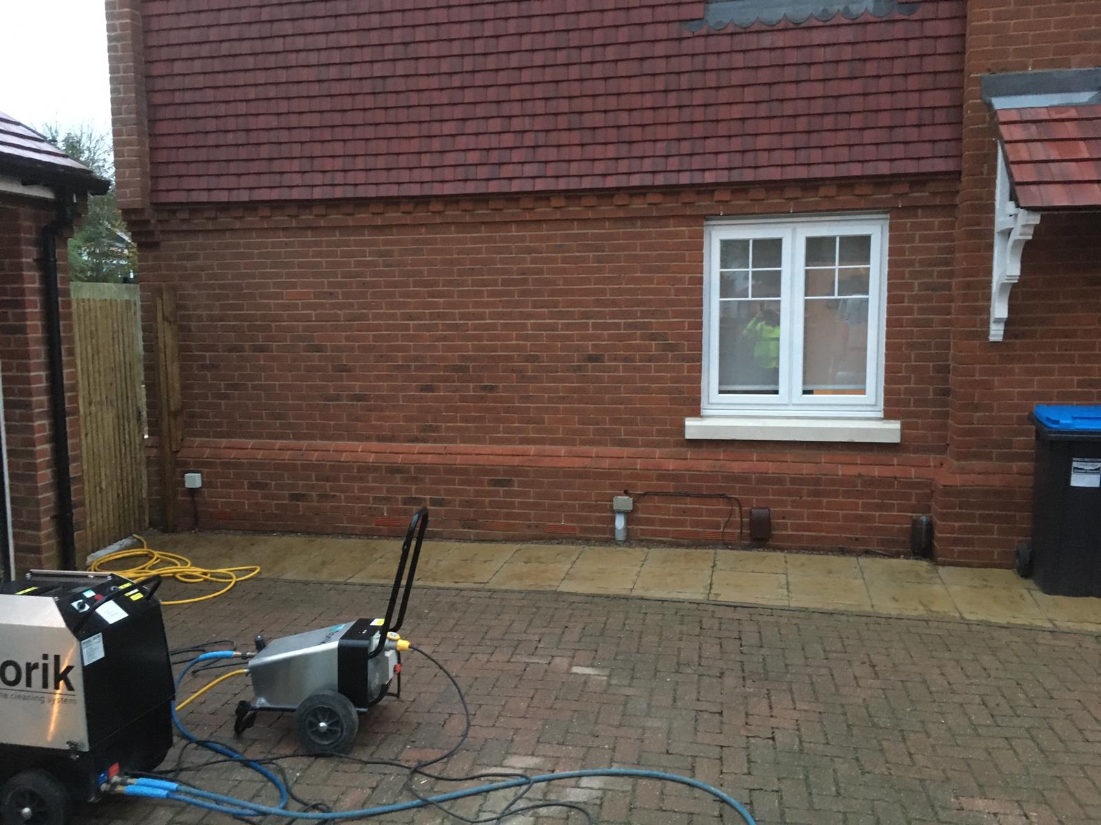 Brick cleaning both the walls of a house and its brick driveway