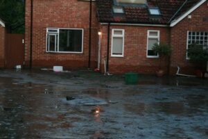 A brick house with damp walls surrounded by flood water.