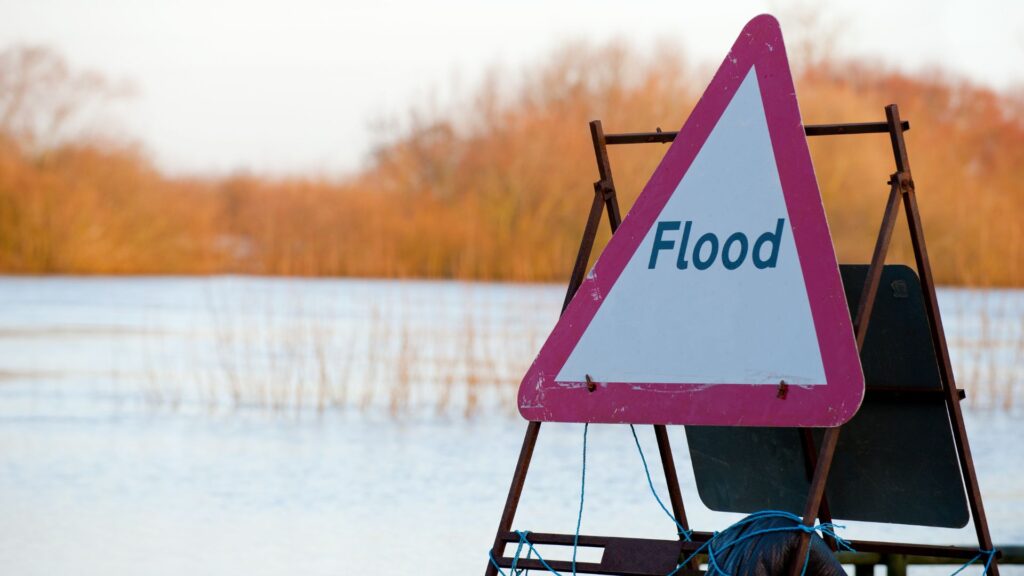 Flood warning sign submerged in flood water.
