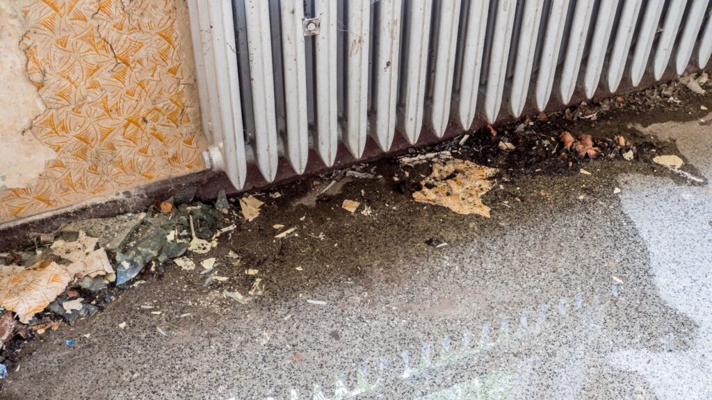 water on floor puddling beneath a radiator.