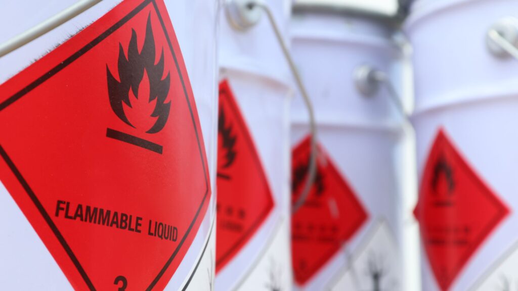 White barrels with red warning stickers reading 'flammable liquids'.