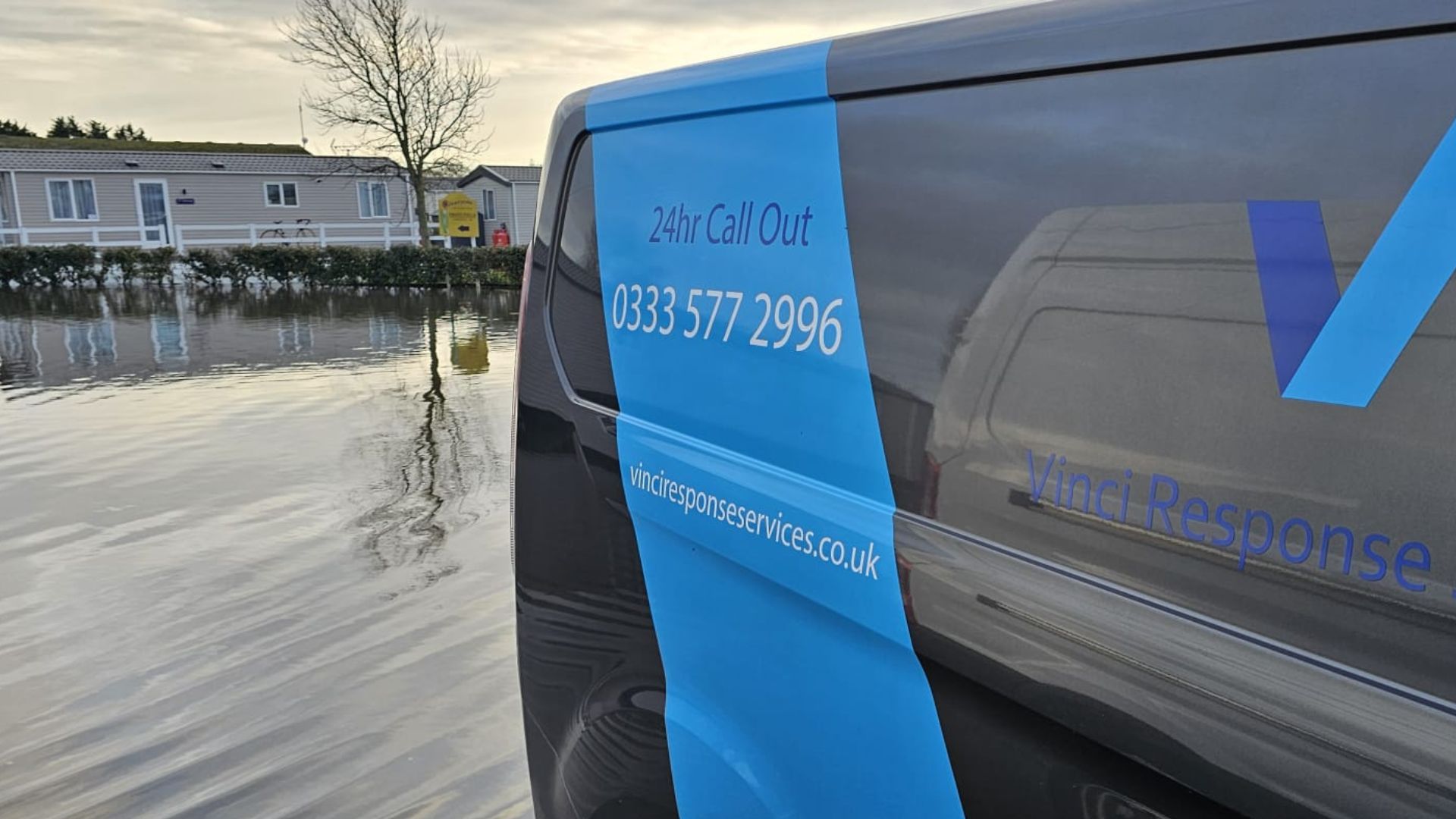 A Vinci Response van with flood water in the background.
