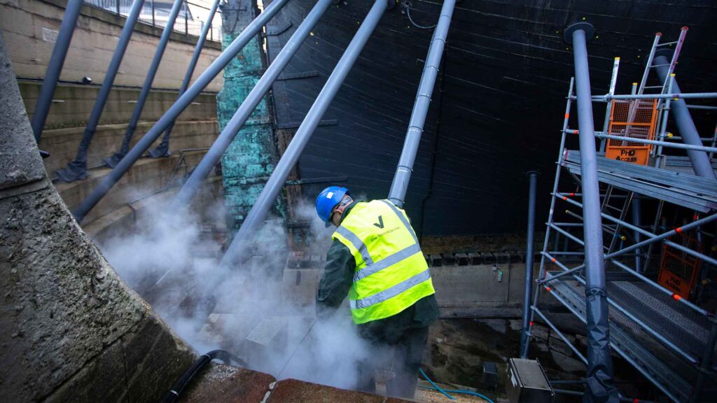 Vinci technicians working to clean the HMS Victory dry dock, at Portsmouth Historic Dockyard.