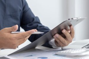 A man in a suit looking at a clipbord to help illustrate Vinci Response's ability to streamline the claims process for loss adjusters.